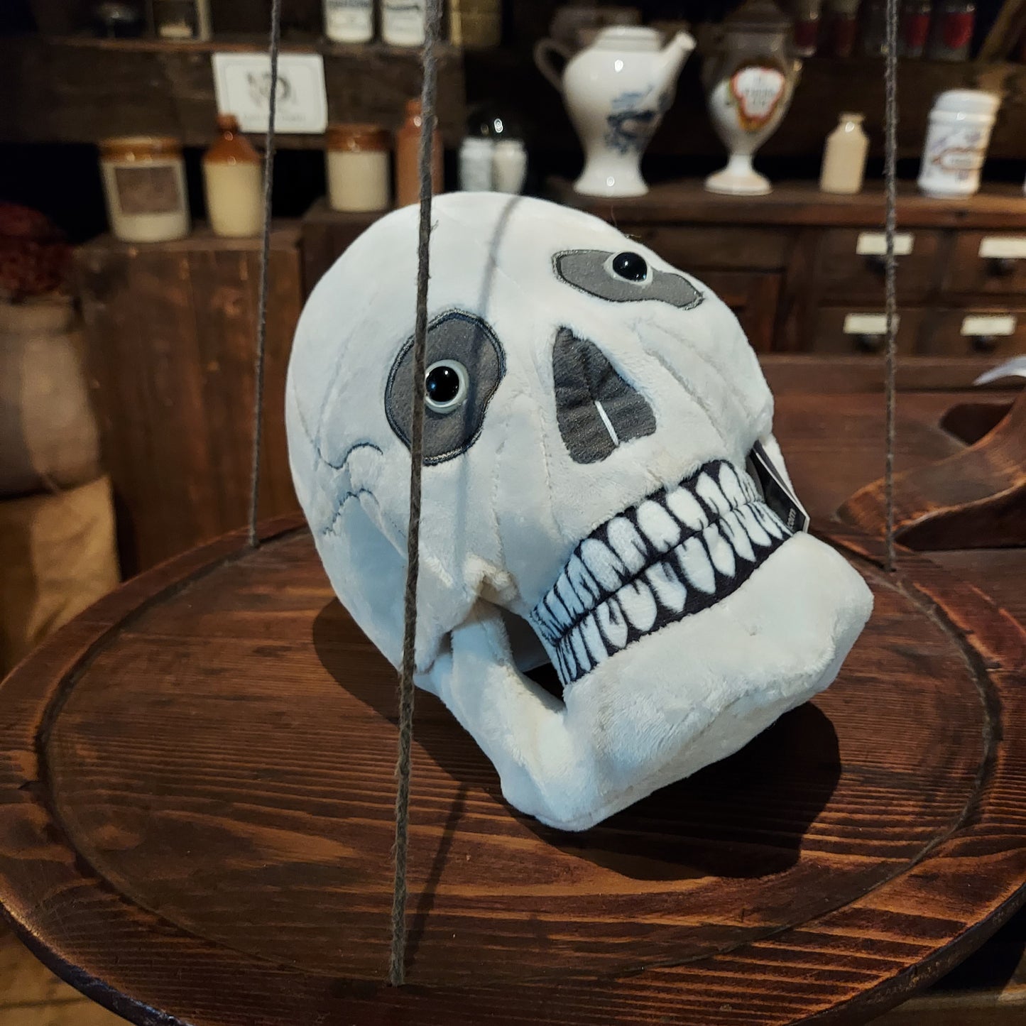A skull plush placed on a wooden scale in the museum
