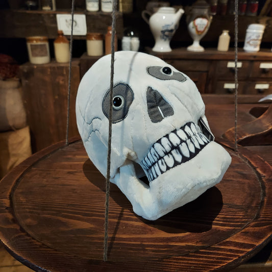 A skull plush placed on a wooden scale in the museum