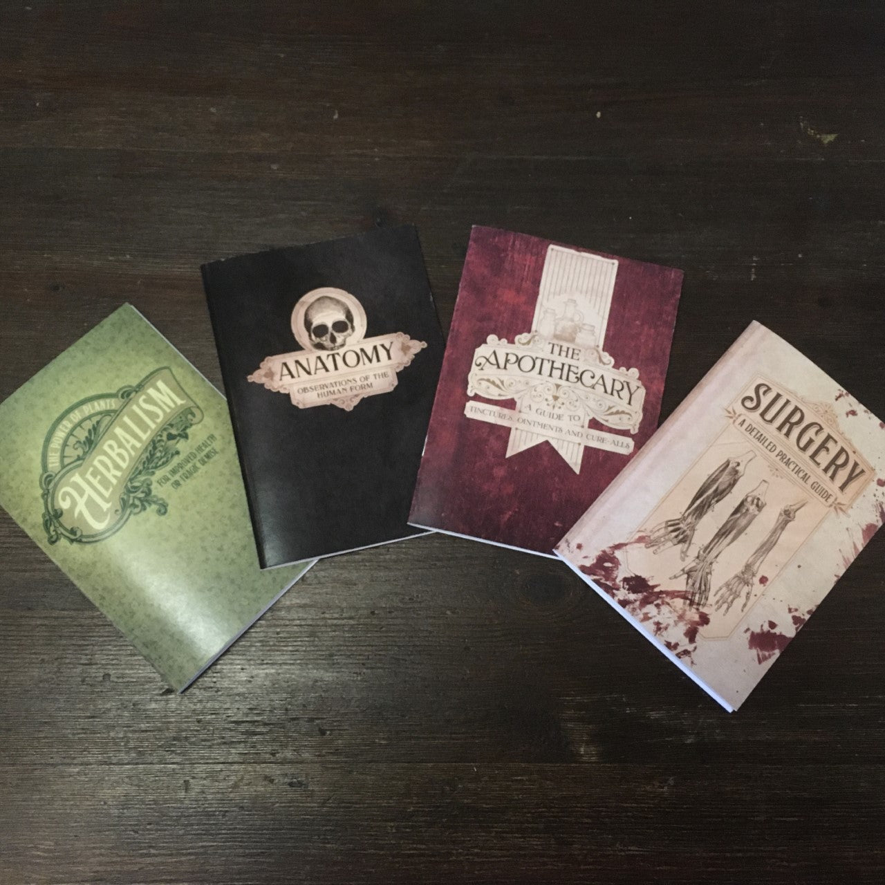 Display of four notebooks: Herbalism, Anatomy, The Apothecary, and Surgery