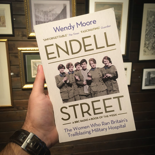 The Endell Street paperback held up in front of collection of historical images of hospitals and London 