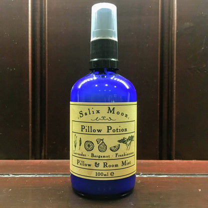 A blue glass bottle of Pillow Potion on a wooden shelf
