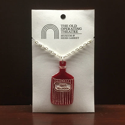 Red pendant in the shape of a bottle with the label 'tinct. belladon'