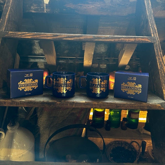 Three blue mugs with gold text on a wooden shelf with a rustic background.