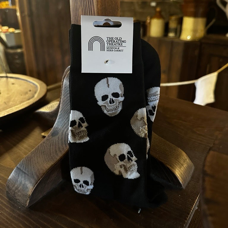 Black socks with skull pattern on a wooden surface, featuring a brand label.