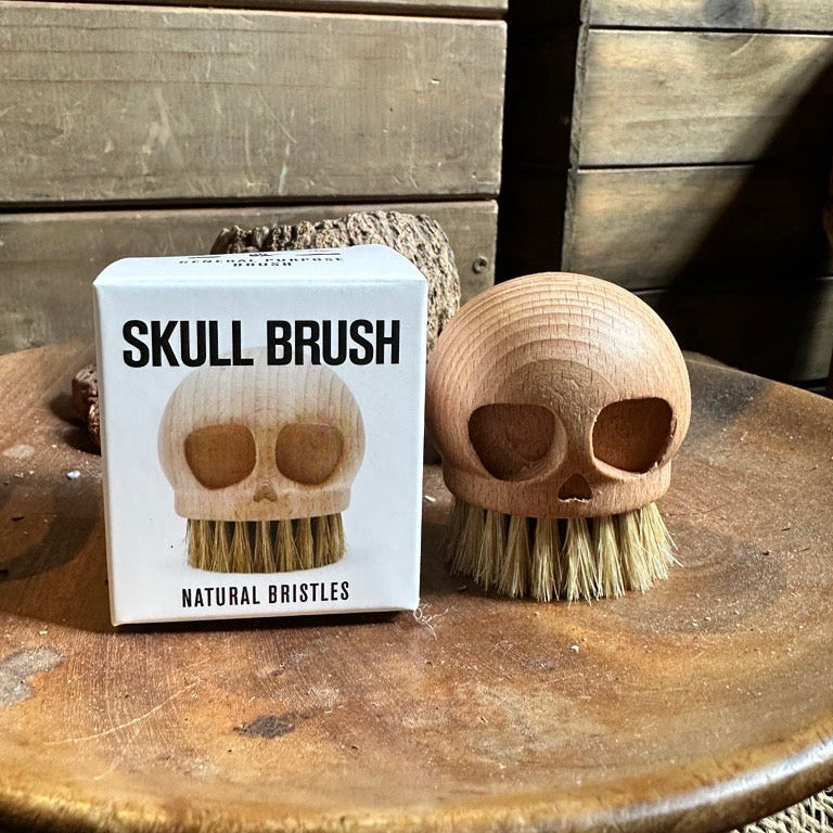 Skull-shaped brush with packaging on a wooden surface
