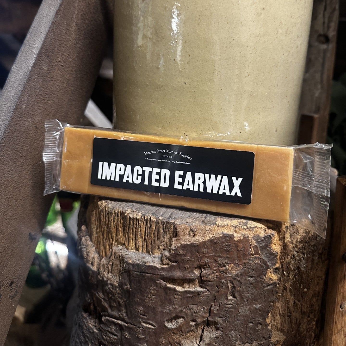 Bar of fudge on a wooden surface, bar is labeled 'Impacted Earwax'.