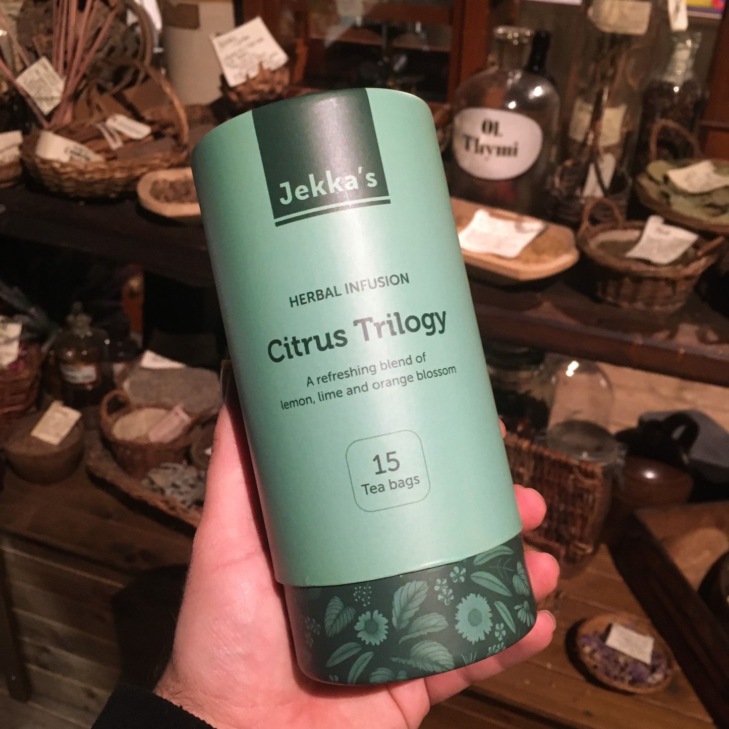 A green cardboard tube of Citrus Trilogy herbal infusion being held up in the museum's herb garret