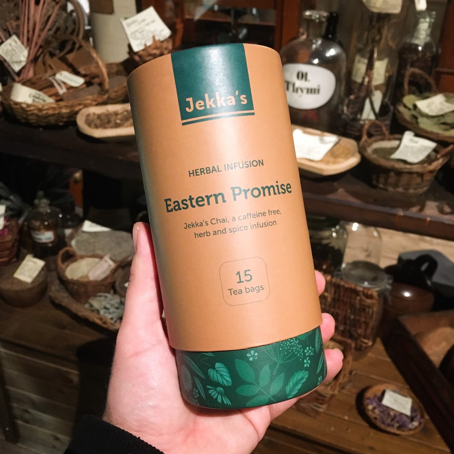 A green and orange cardboard tube of Eastern Promise herbal infusion being held up in the museum's herb garret