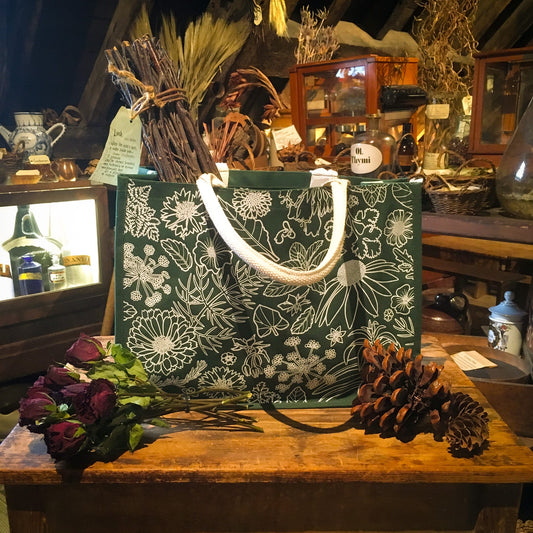 Green bag with white outline decoration of flowers and leaves; it has thick white handles