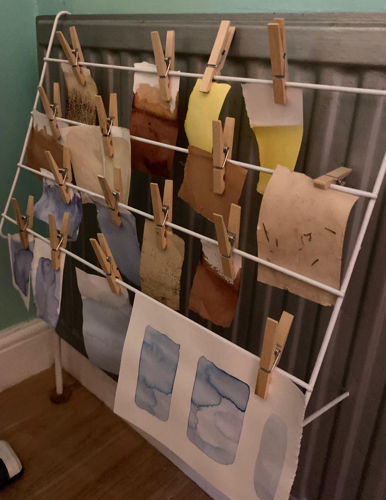 Dyed sheets of paper hanging to draw against a radiator