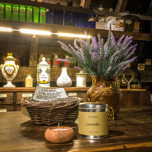 A terracotta tealight and a lavender candle tin on the apothecary counter in the museum, next to a basket of dried lavender and a jar filled with lavender sprigs