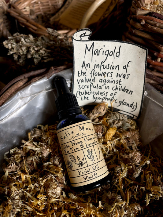 A bottle of facial oil in a basket of dried marigold flowers