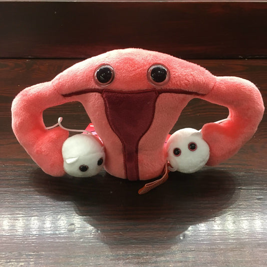 Pink plush toy in the shape of a uterus with white egg cells