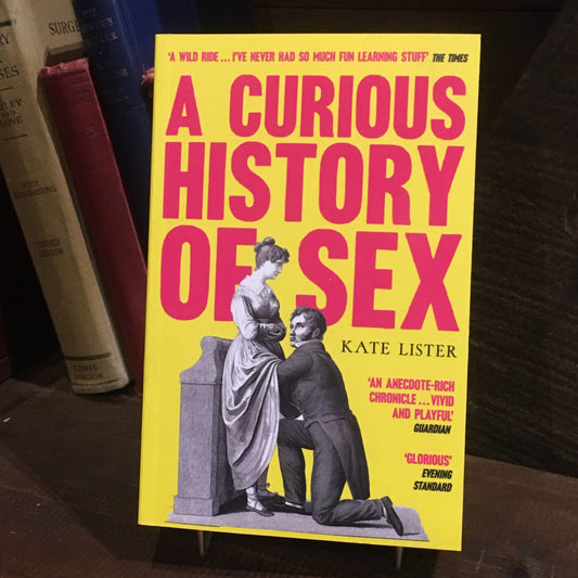 The paperback of A Curious History of Sex on a shelf in front of some old hardback books