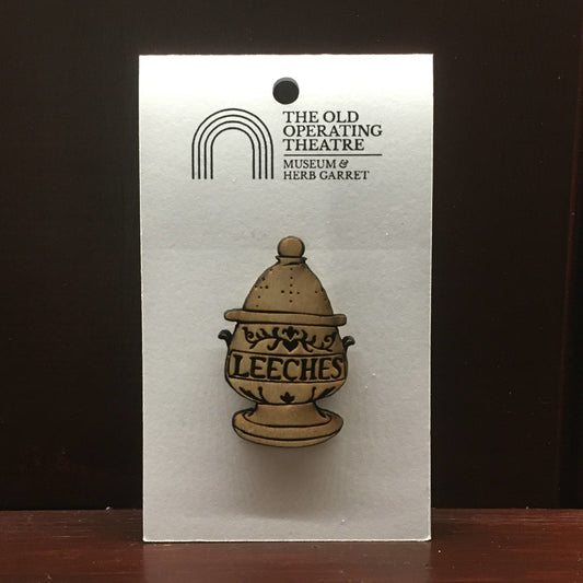 Egg-shaped wooden pendant designed as a jar with the word 'leeches' across the centre. Suspended on a metal chain.