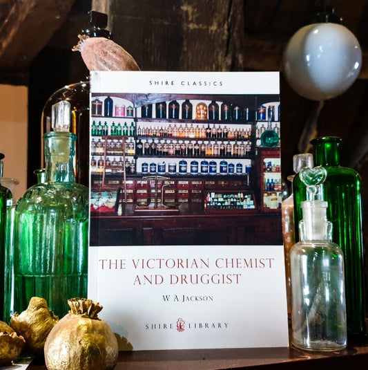 A copy of The Victorian Chemist and Druggist displayed in the museum next to glass bottles