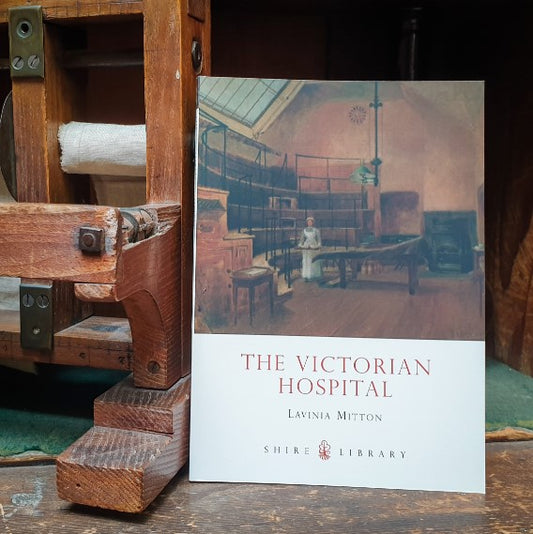 The book The Victorian Hospital next to a 19th century bandage dispenser