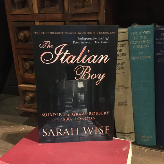 The Italian Boy book displayed in front of a row of hardback books