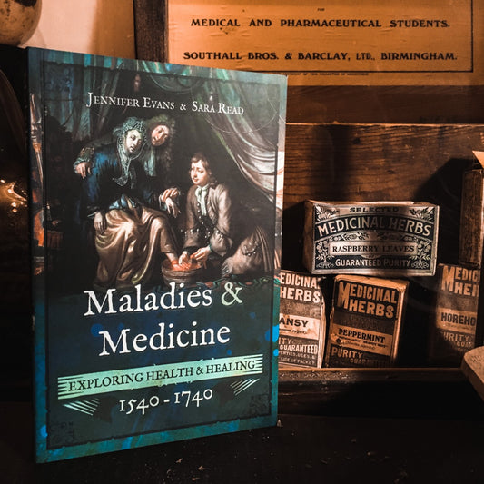 The Maladies and Medicine book next to old medicinal herb boxes