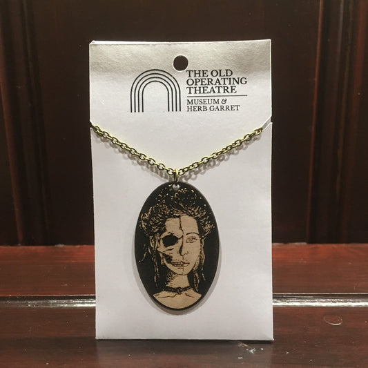 Wooden pendant with a woman's face that is half skull