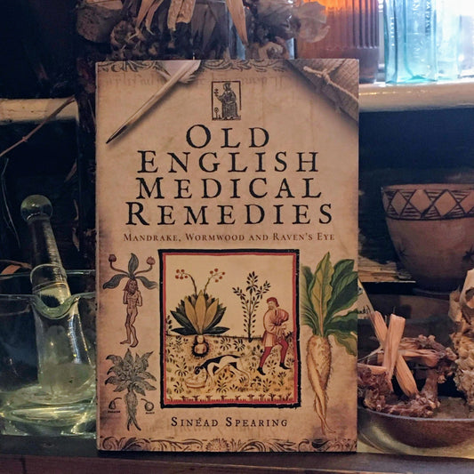 The Old English Remedies book displayed in the museum next to a pestle and mortar and dried herbs