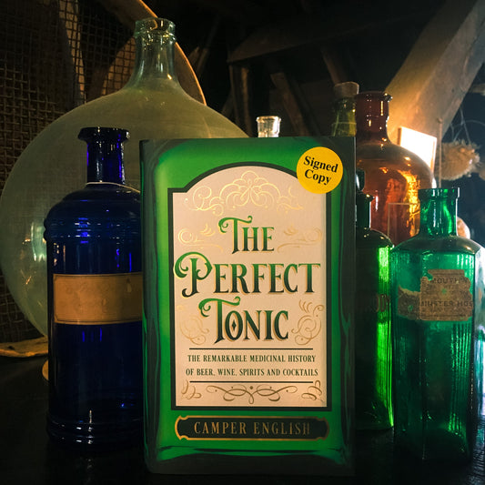 A copy of The Perfect Tonic, displayed in the museums next to blue and green glass apothecary bottles