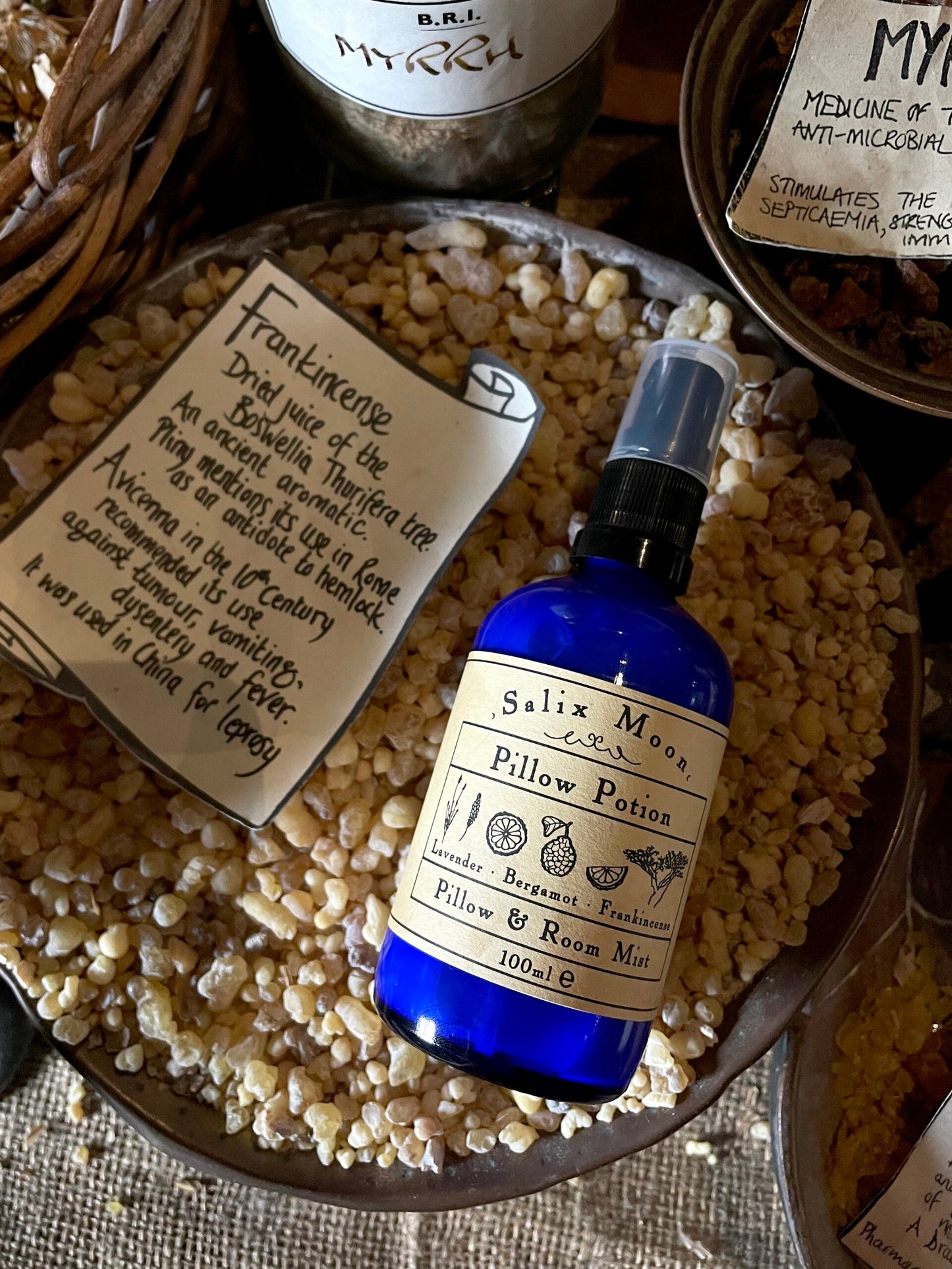 A blue glass bottle of Pillow Potion in a bowl of frankincense in the museum's herb garret