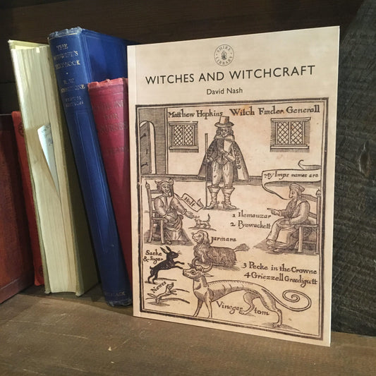 The book Witches and Witchcraft on a shelf next to some old hardback books