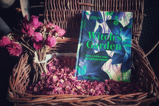 A copy of the book Witch's Garden in a basket of dried rose petals