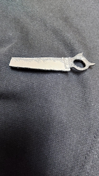 A silver saw brooch lying on black fabric