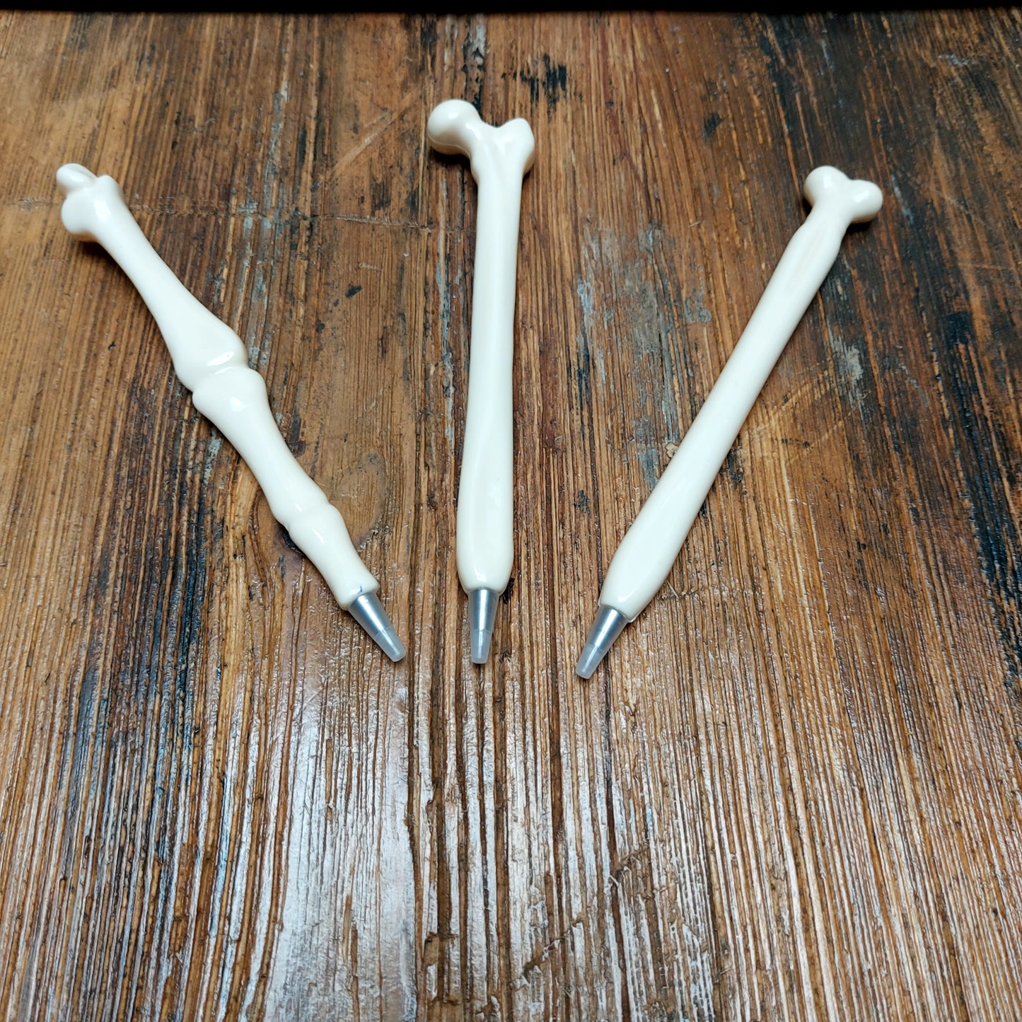 Three pens in the shape of different bones and joints, on a wooden surface