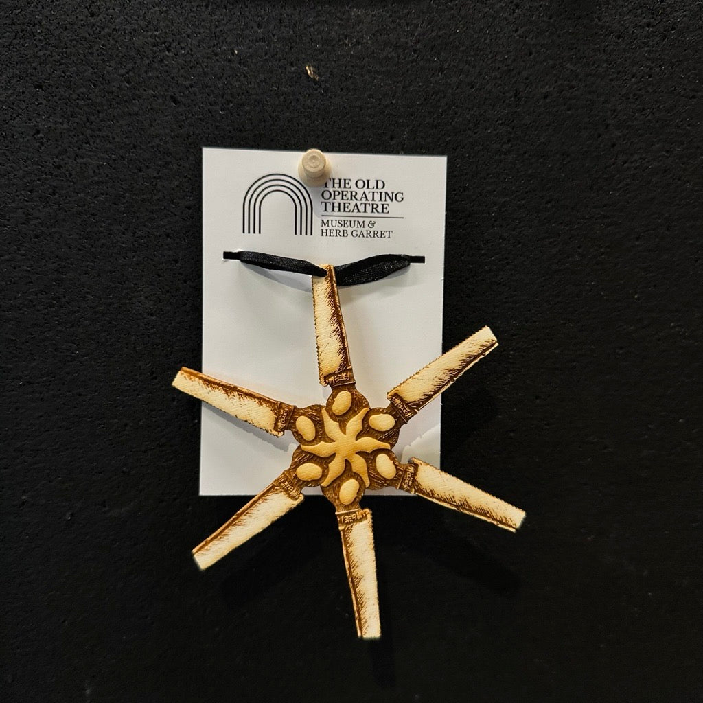 Decorative star-shaped surgical saws on a card with 'The Old Operating Theatre' label against a black background