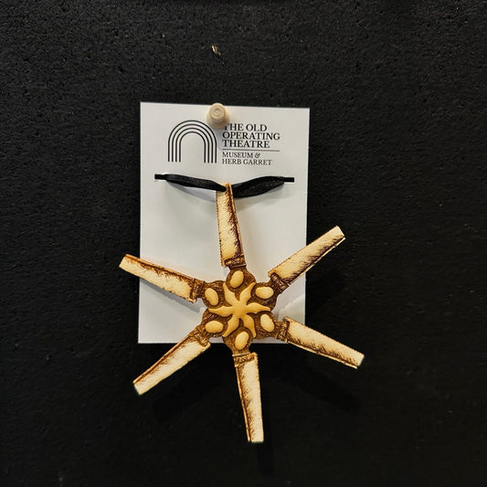 Decorative star-shaped surgical saws on a card with 'The Old Operating Theatre' label against a black background