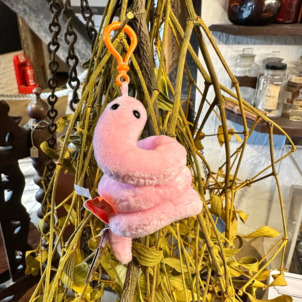 Pink plush keychain with an orange clip hanging from a decorative wreath.