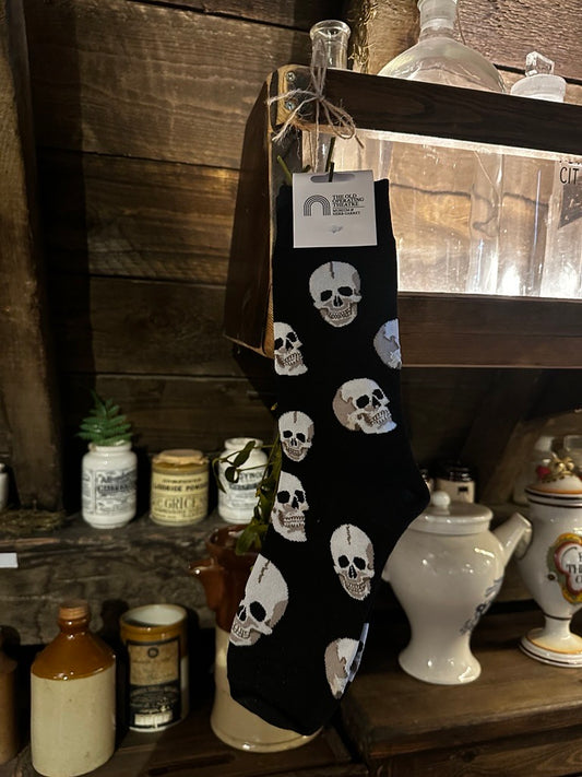 Black sock with skull patterns hanging on a wooden surface with decorative bottles in the background