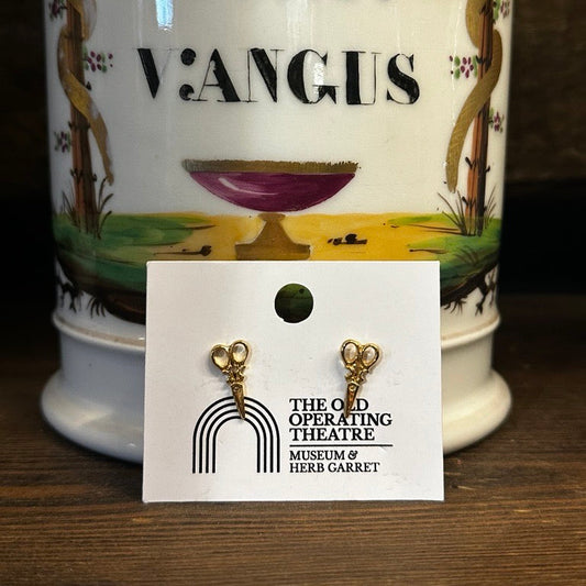 Decorative vase with 'Cort Vangus' text and a pair of gold earrings on a card in front.