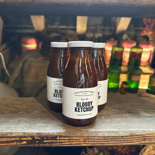 Three bottles of Bloody Ketchup on a wooden shelf with blurred background